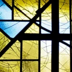 A stained-glass window depicting an Anglican cross with the American flag in the background. - American Anglican Church