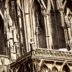 A close-up image of a beautifully carved statue of a saint or religious figure, set against the backdrop of a Gothic cathedral. - Christian churches, statues, religious art